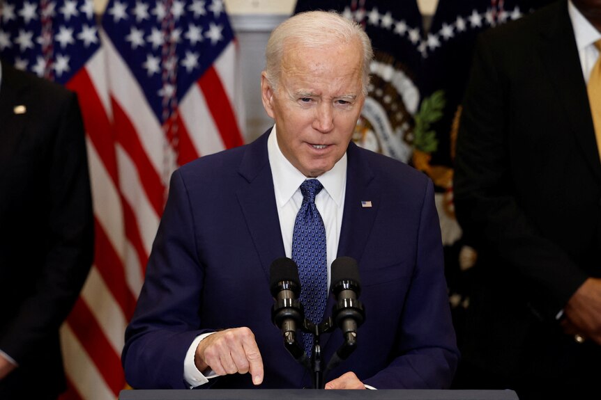 Close up US President Joe Biden speaking at lectern.