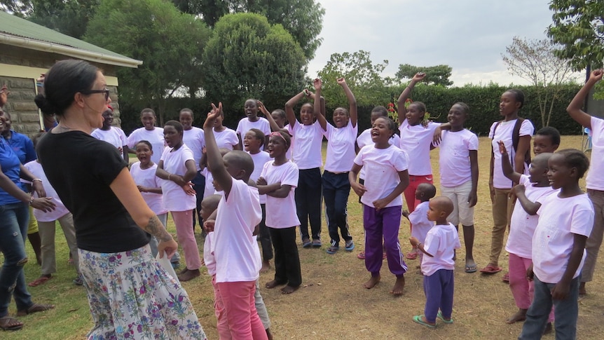 A woman stands with smiling African children