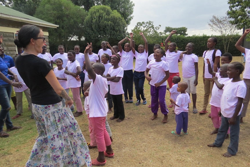 A woman stands with smiling African children