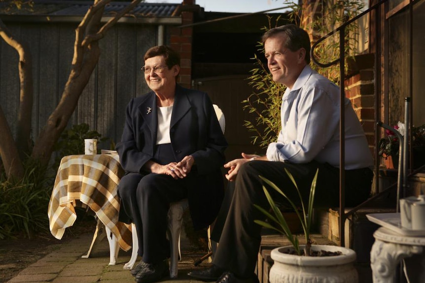 Ann Shorten sits on a plastic stool while Bill Shorten sits on some stairs.