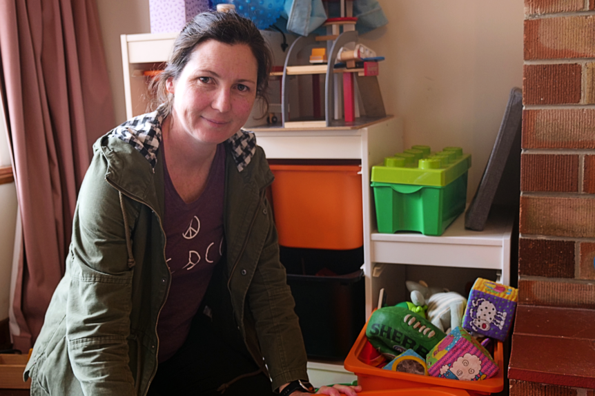 A woman puts away her children's toys in the playroom