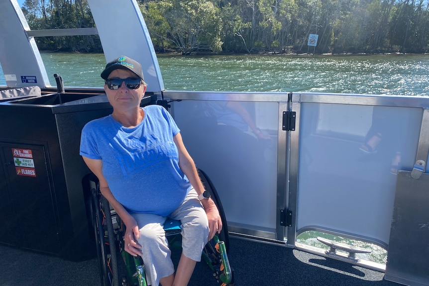 A woman in a blue shirt sitting in a wheelchair on the boat
