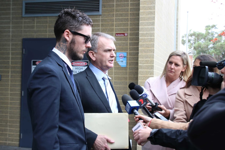 Bradley Joseph Mitchell stands in front of the court with his lawyer, in front of journalists.