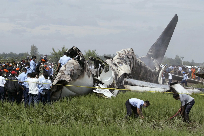 Men climb on to the smoking wreckage of a passenger plan