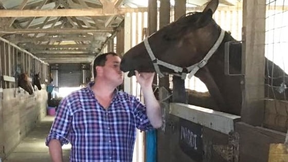 Scott Brunton with a horse in a stable.