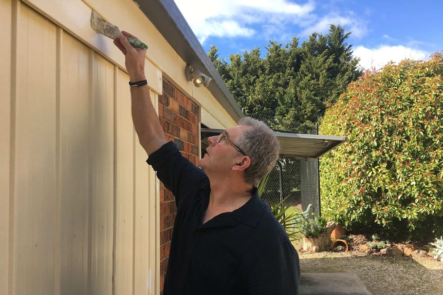 David Halliwell painting a house.