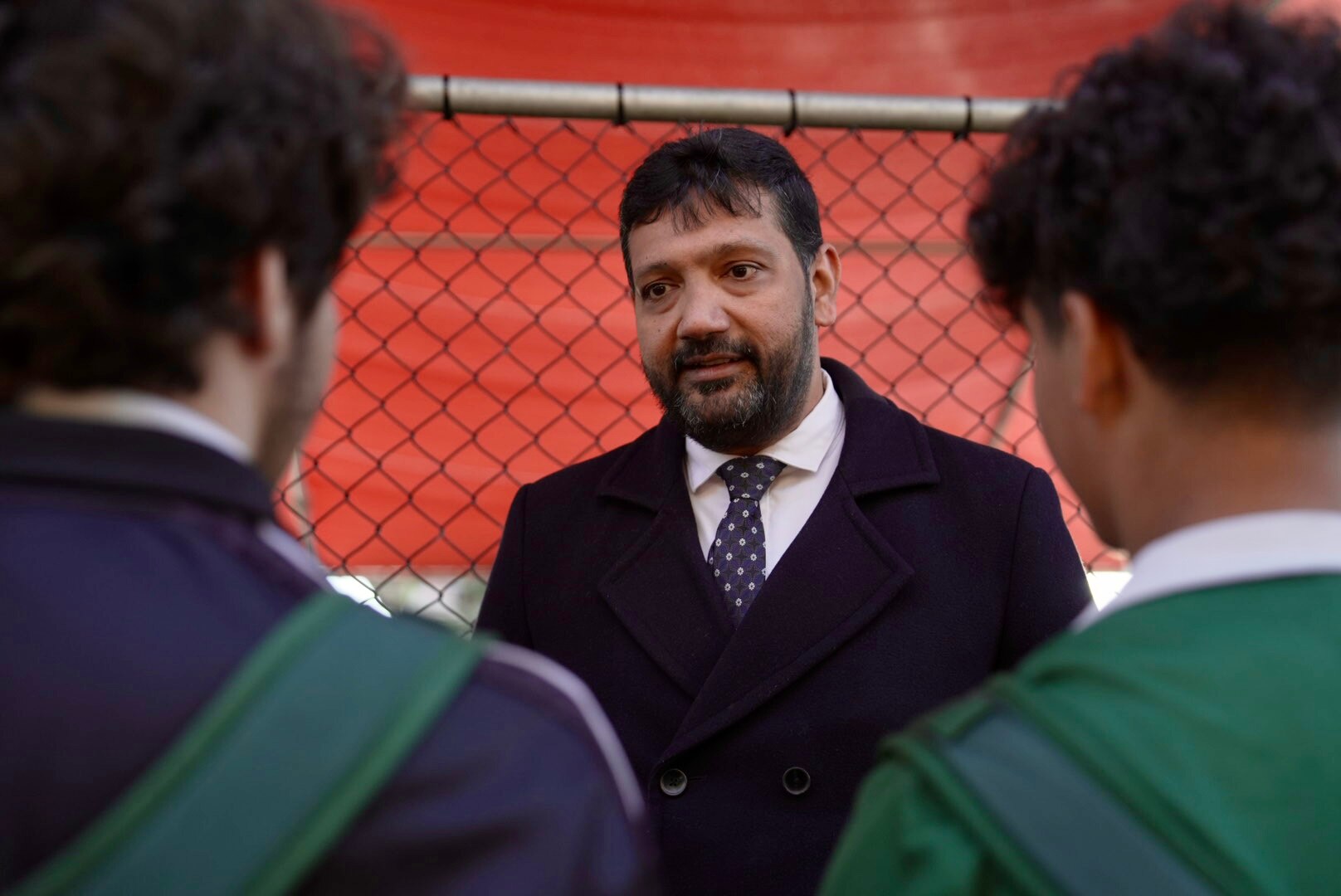 Dr Ali Kadri talks with two Palestinian students on school grounds.