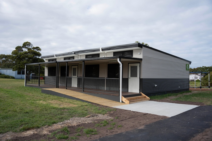 A demountable building sits on a grassy field.