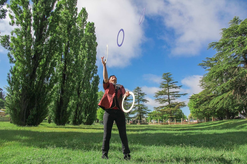 A woman juggling hoops at a park