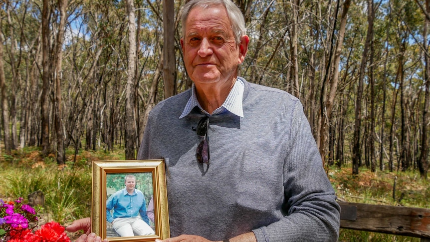 Max Davidson holds a photo of his son, Stuart, who died in a bushfire at Linton in 1998.
