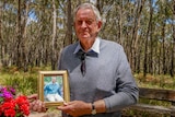 Max Davidson holds a photo of his son, Stuart, who died in a bushfire at Linton in 1998.