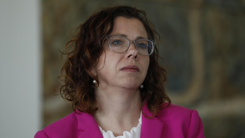 Amanda Rishworth wearing a pink blazer and white blouse, looking to the right