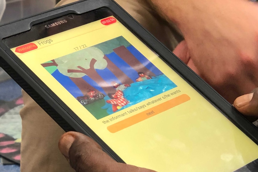 An Aboriginal man holds an iPad as part of language research at Balgo.