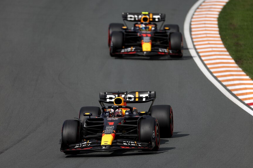 Two dark blue F1 cars lead a race, lined up in front of each other.