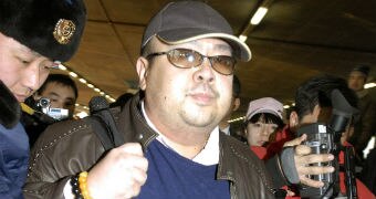 A man in a hat is surrounded my media as he walks through at Beijing airport