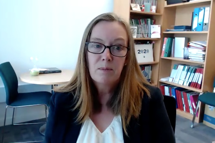 A woman in glasses sits in an office.