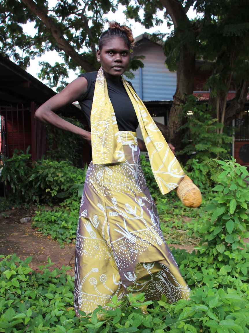 An Aboriginal woman modelling a yellow and purple garment with an Aboriginal design.