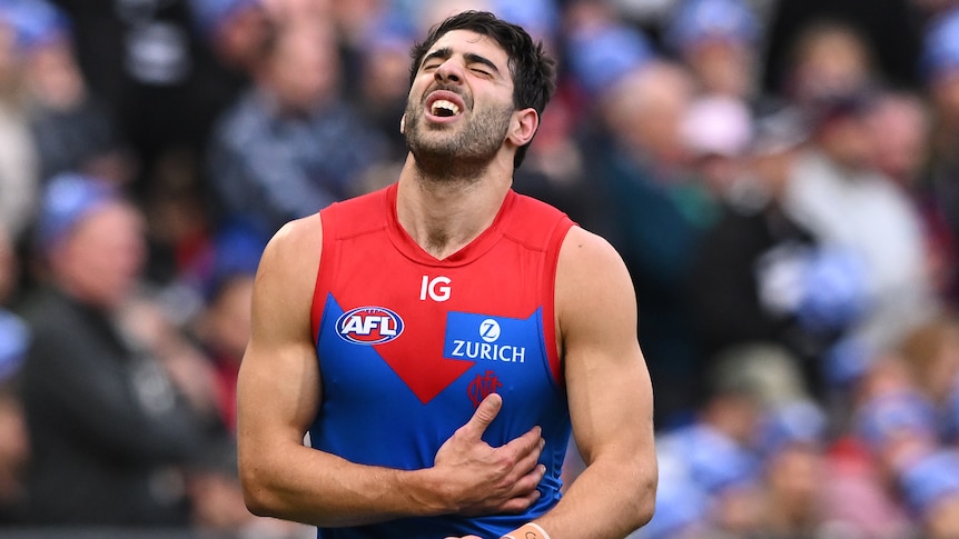 Christian Petracca of the Demons exiting the field, whincing in pain, holding his side