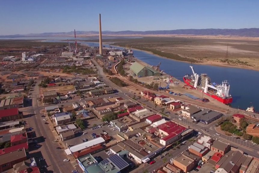 An aerial view of a regional city with a smelter funnel looming over it.