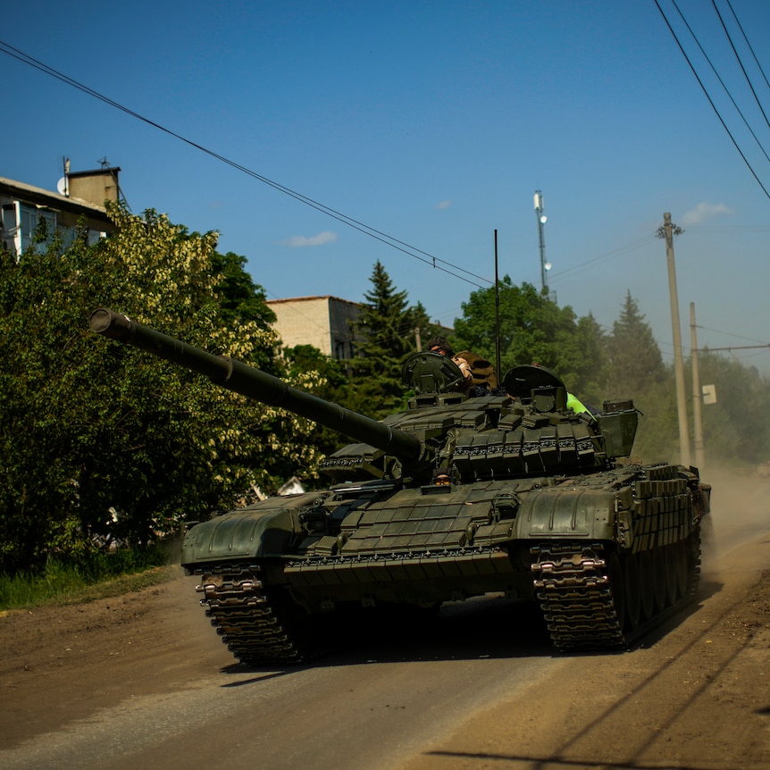 An army tank drives down a residential Ukrainian street