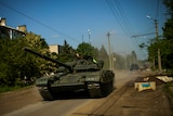 An army tank drives down a residential Ukrainian street