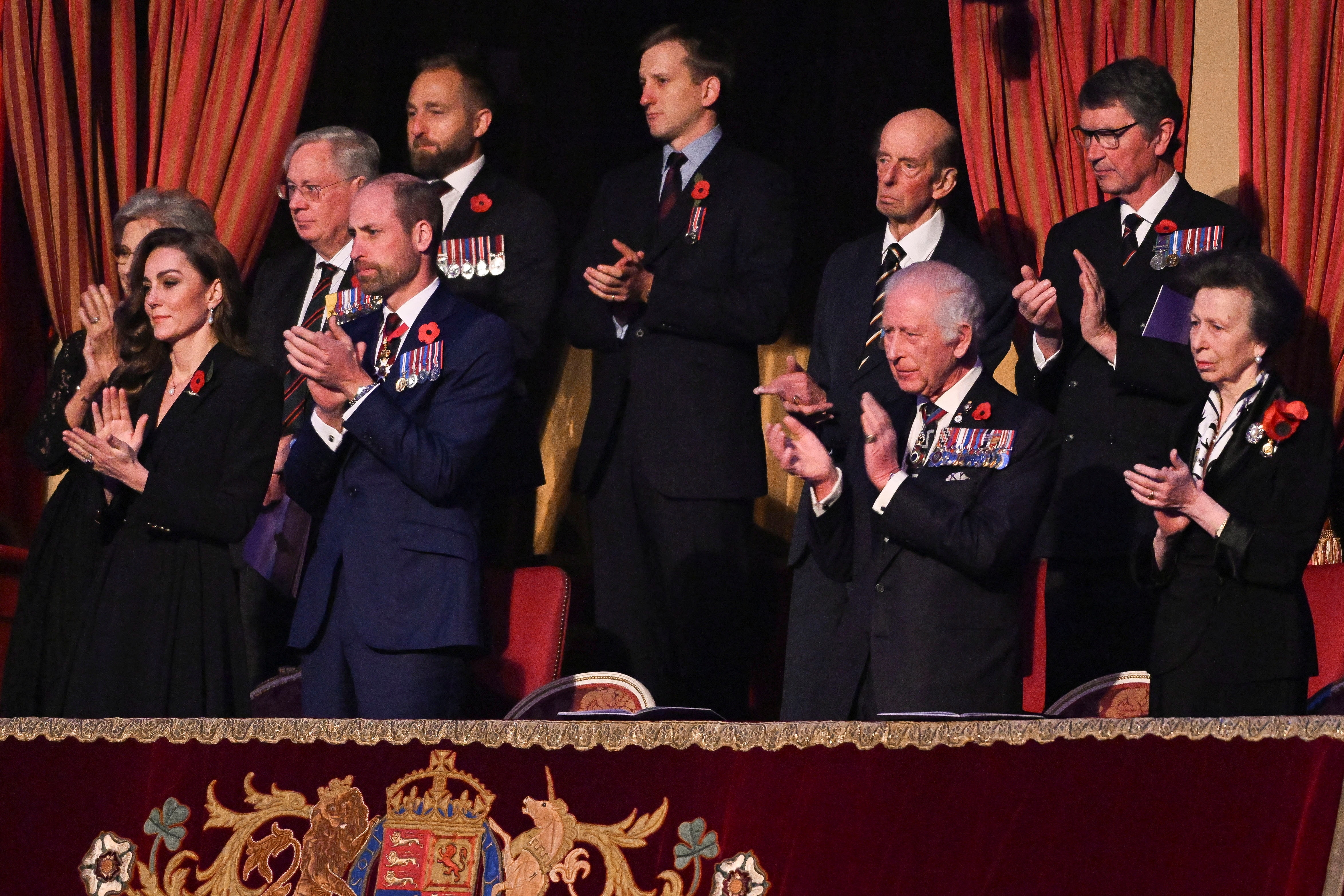 The royal family standing and applauding veterans at an event