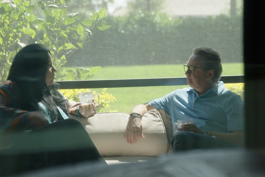 Man and woman sitting on a porch having a conversation.