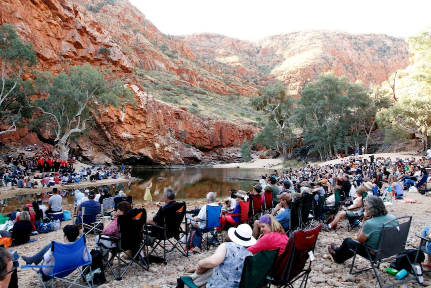 people sitting on chairs listening to a choir inside a gorge