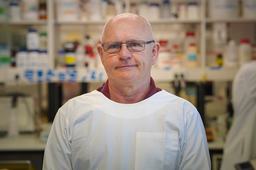 A professor in a lab wearing a white coat.