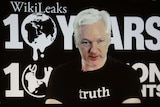Julian Assange participates via video link at a news conference.