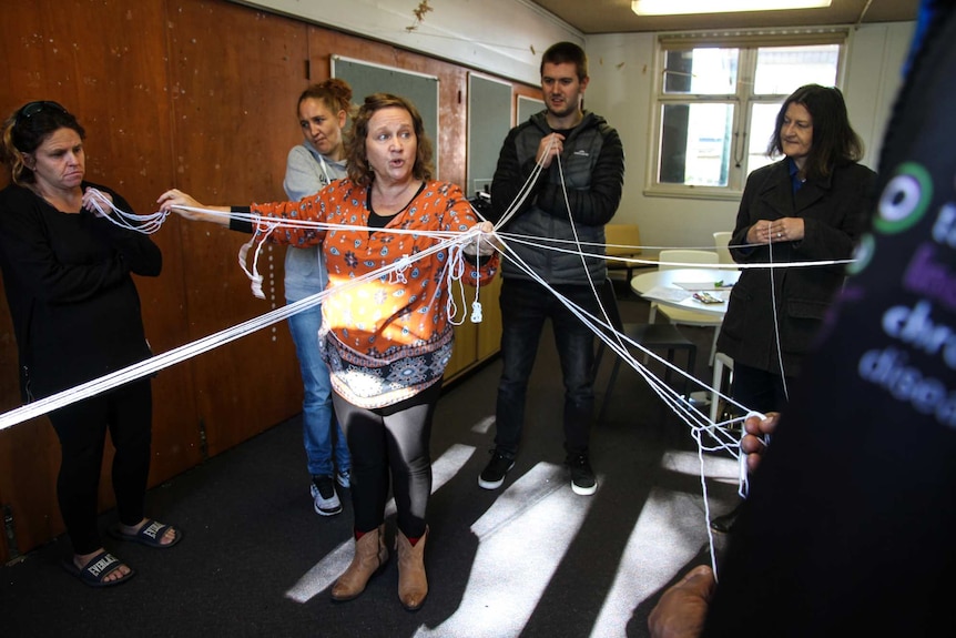 A woman conducts a workshop in a classroom with parents.