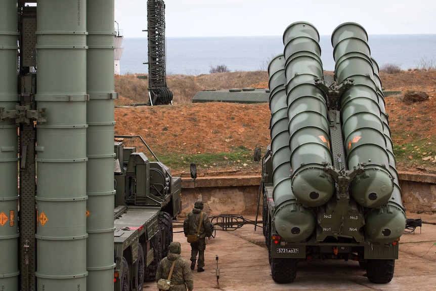 Russian troops walk next to a surface-to-air missile system in Crimea.