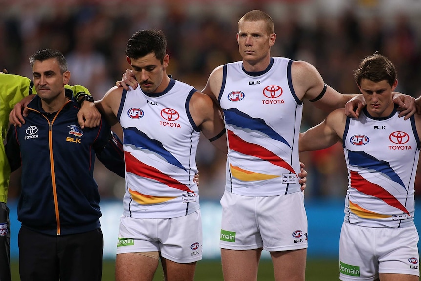 Paying respect ... Interim Crows coach Scott Camporeale (left) and captain Taylor Walker (second from left) stand alongside the Crows players for a minute's silence