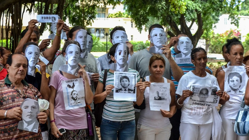 Cuban dissidents pose wearing masks depicting US president Barack Obama