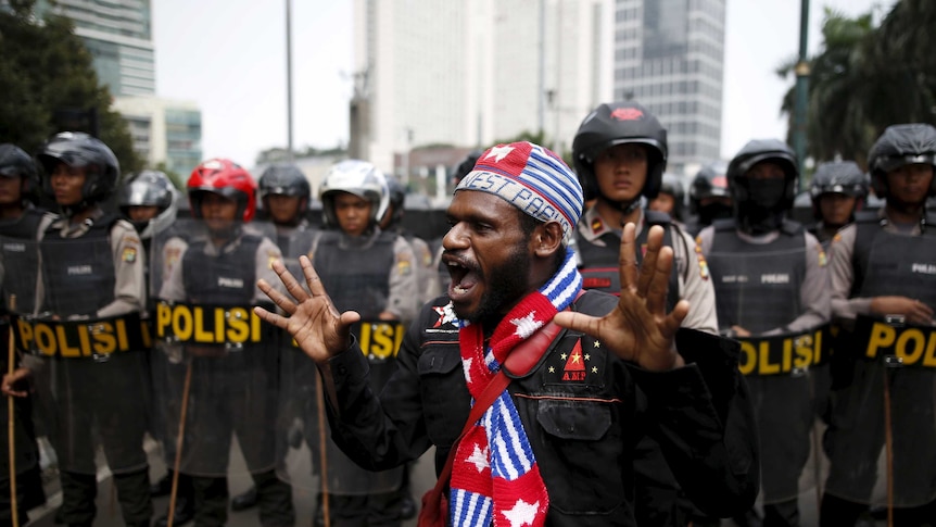 An activist shouts near a police line during a rally.