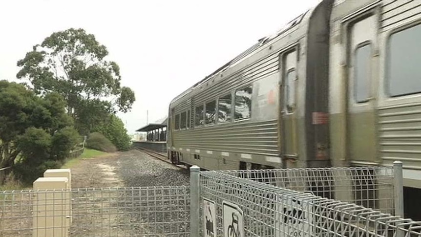 Heading past a station, the Australind is on its way to Bunbury from Perth