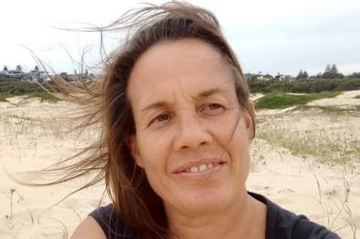 A close up of a woman who is sitting on the sand at a beach