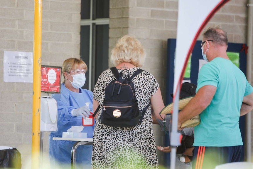 Two people are offered hand sanitiser as they arrive at a COVID testing clinic in Perth.