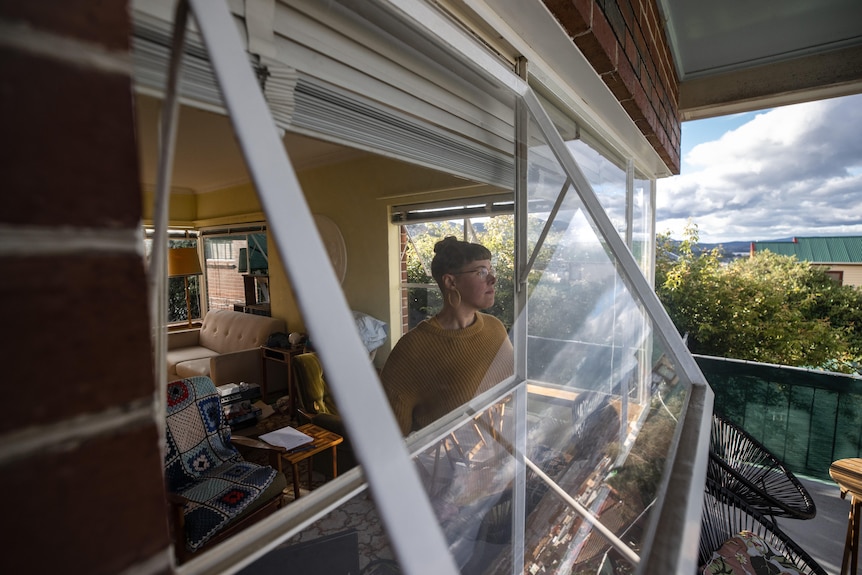 A woman looking pensively out the window in a house