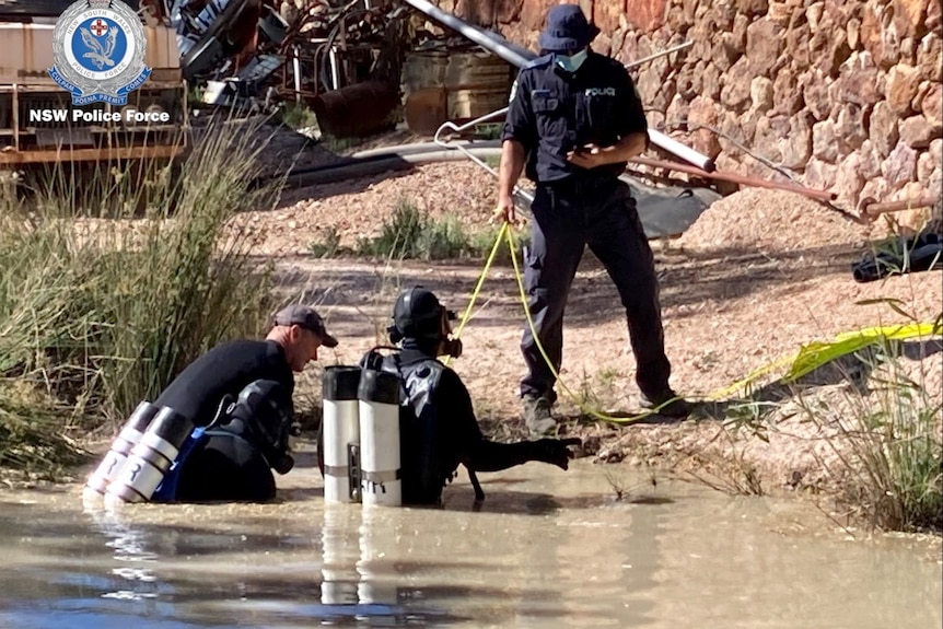 Three divers in a pond. Photo has police logo.