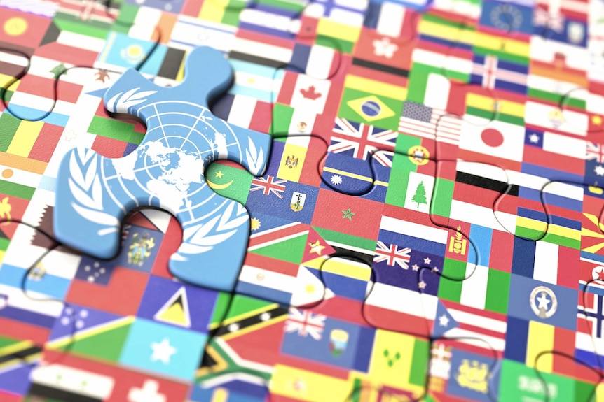 A close up of puzzle pieces featuring world flags and the UN flag sitting higher than the other pieces.