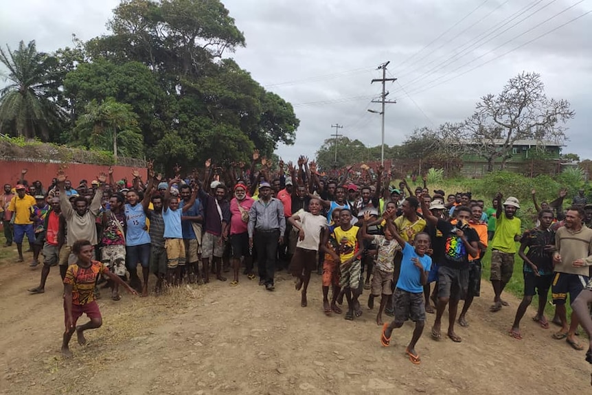 A photograph showing members of the community on Daru Island gathered together on a dirt road.
