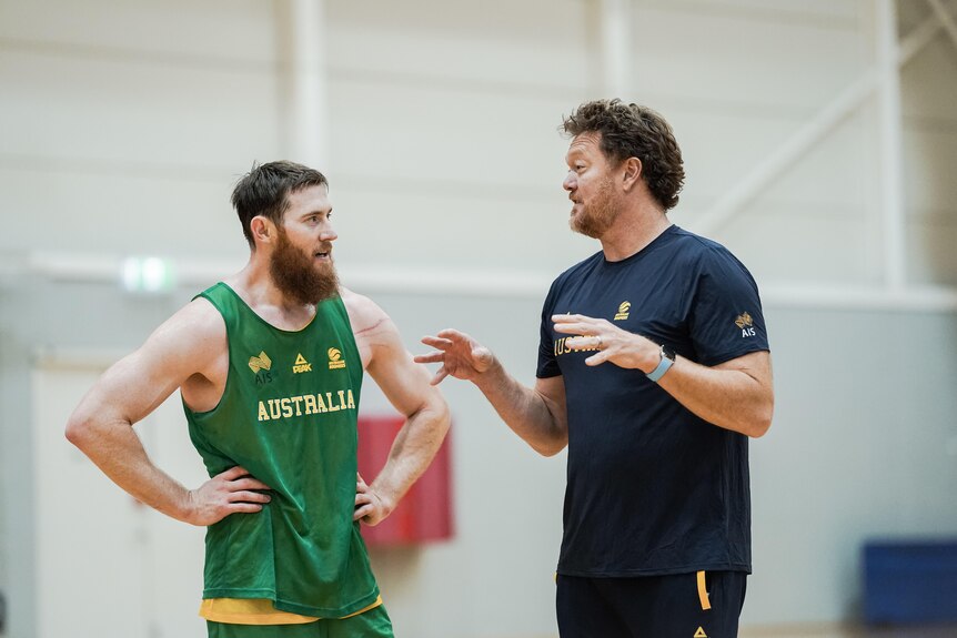 Boomers centre Aron Baynes speaks to Australian men's team assistant coach Luc Longley at training.