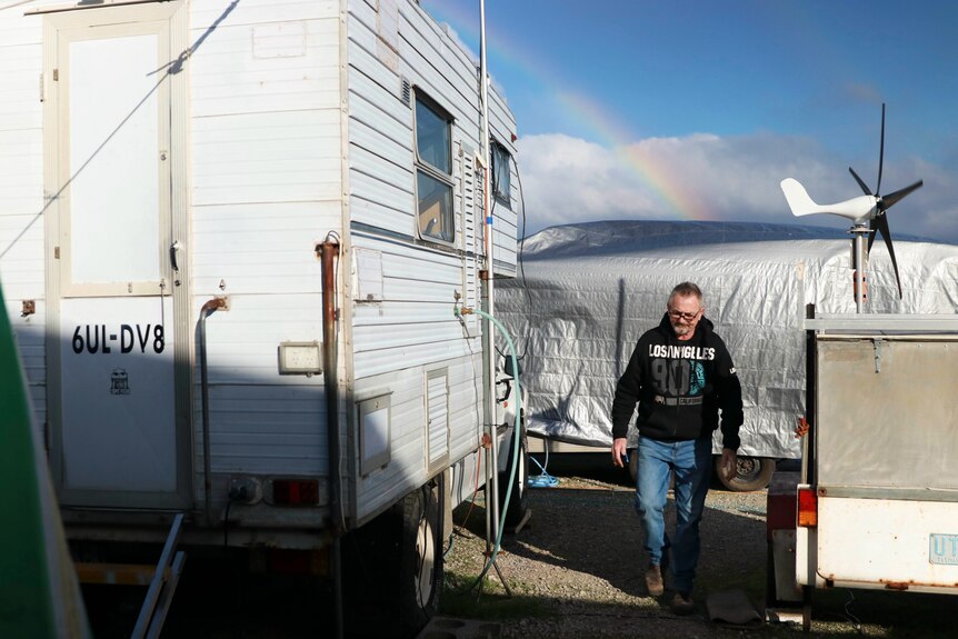 A man walks past campervans and trailers.
