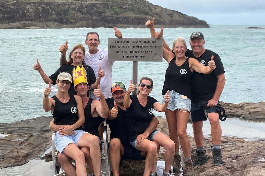 A group of people standing around a sign that marks the northernmost point on the Australian continent.