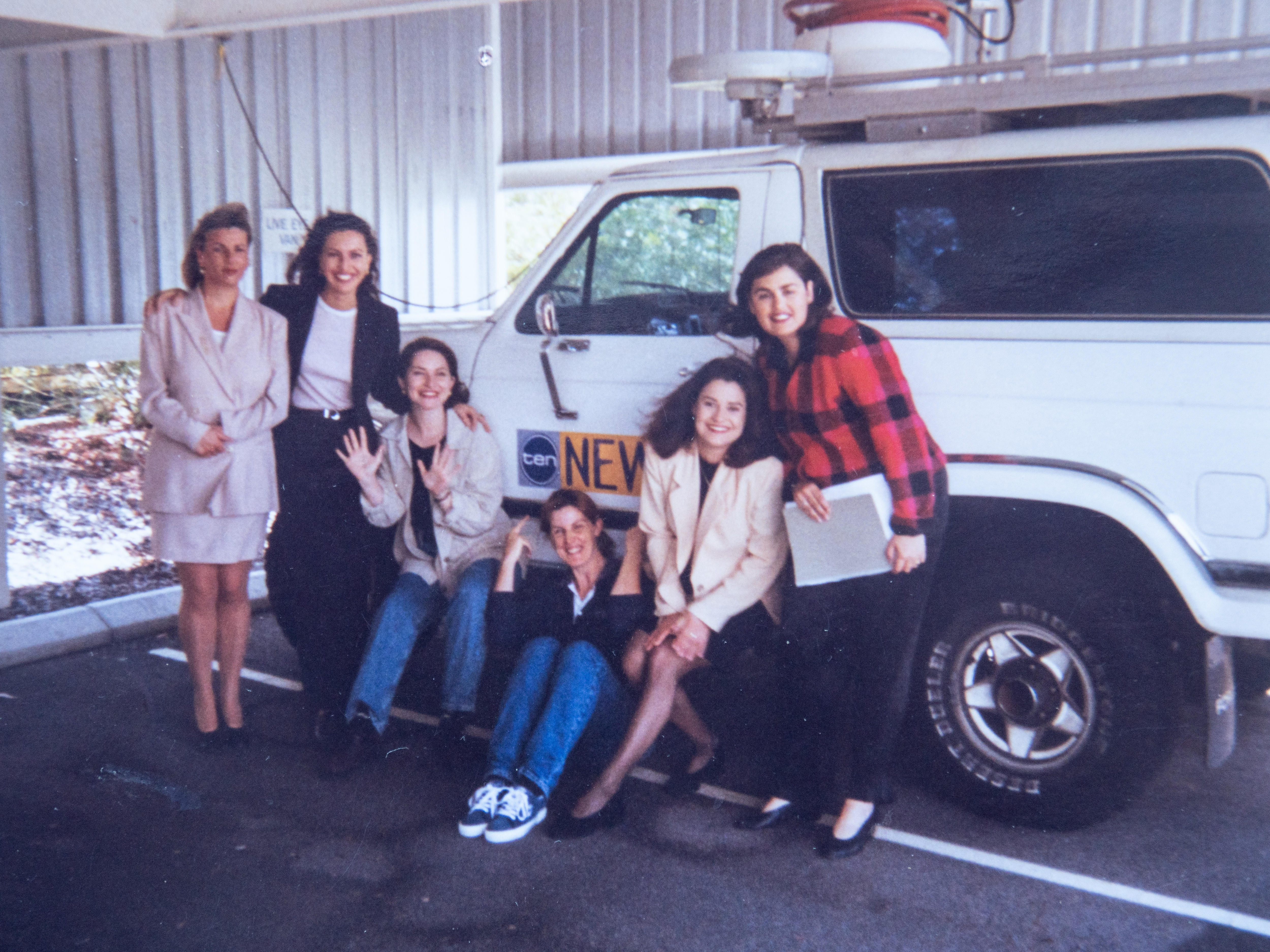 Group of women pose for photo next to white 4WD in garage
