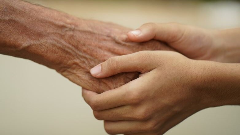 Photo of a young pair of hands holding an older pair of hands 