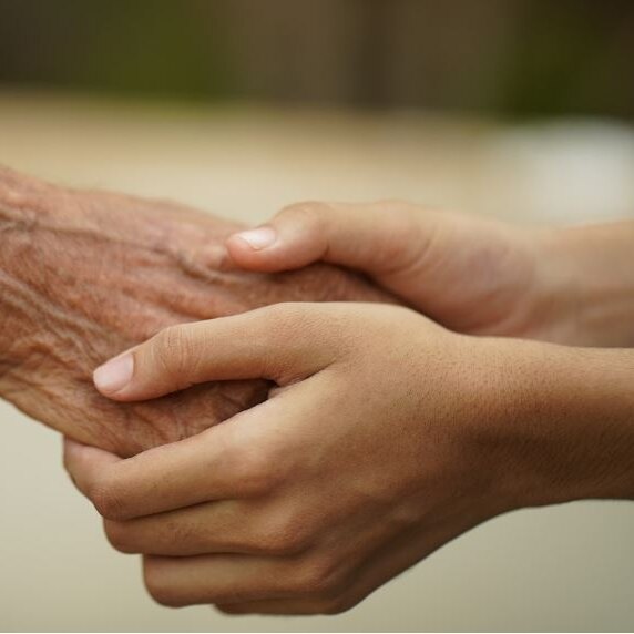 Photo of a young pair of hands holding an older pair of hands 