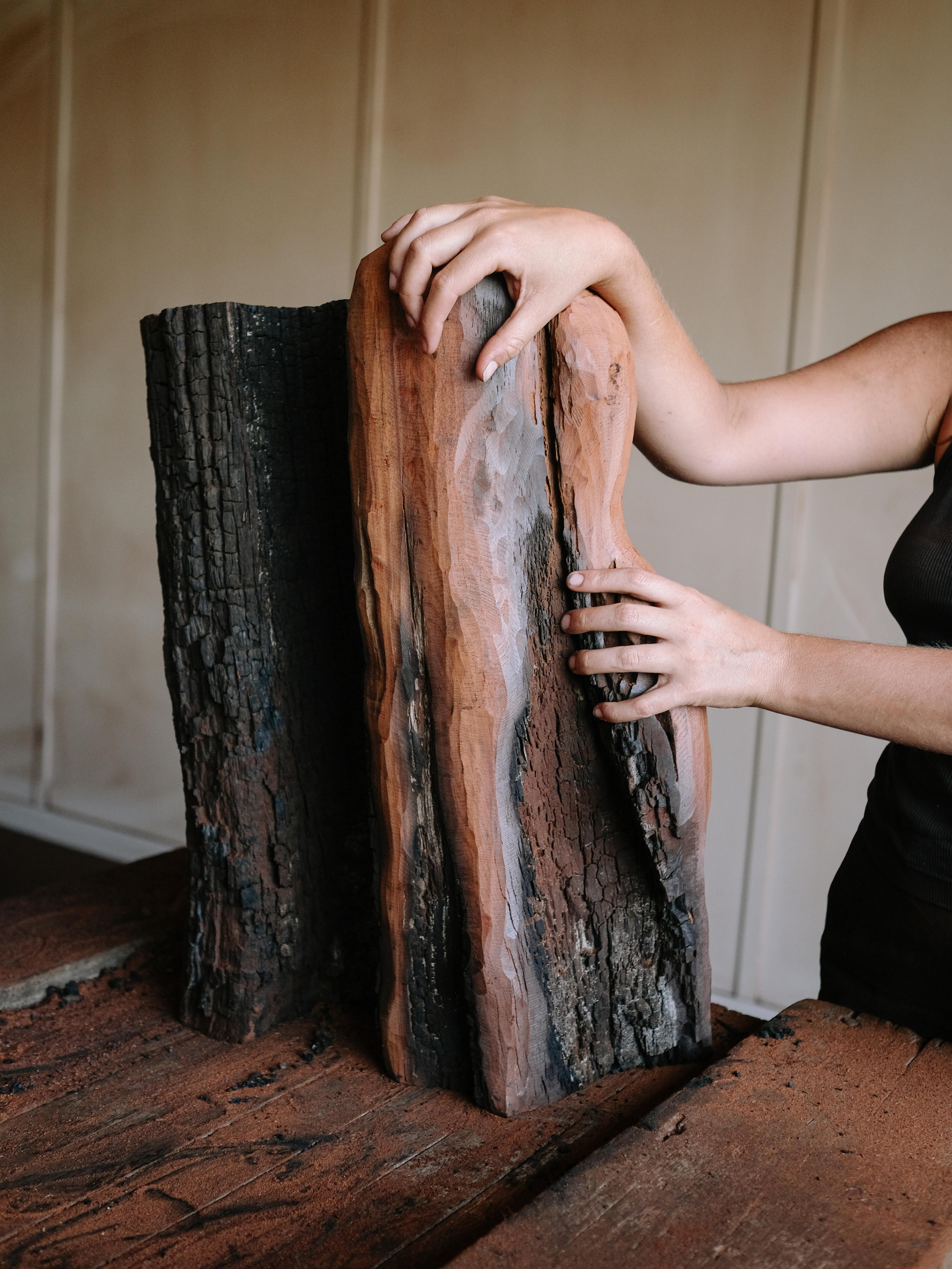 The artist holds a large piece of partially carved wood