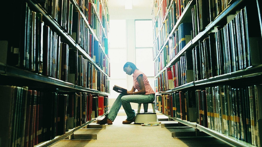 Female student reading a book in a university library